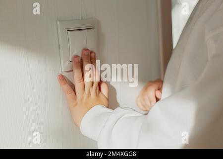 Hand pressing light switch on the wall Stock Photo