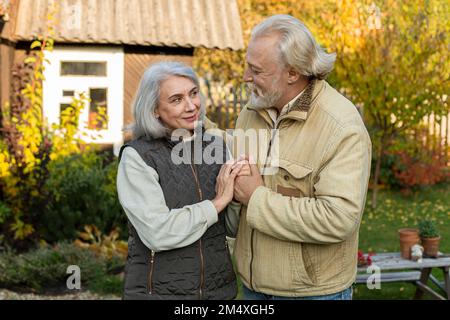 Affectionate senior couple holding hands in garden Stock Photo