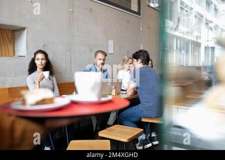 Men and women sitting and having coffee in cafe Stock Photo