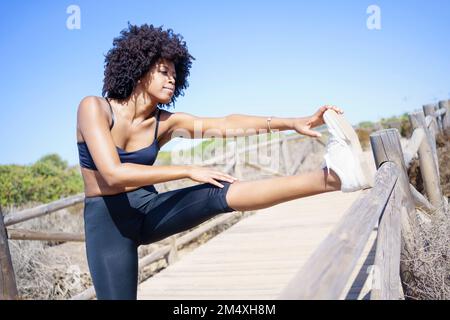 Young woman practicing stretching exercise on sunny day Stock Photo