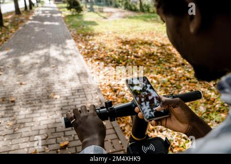 Man with push scooter using app on smart phone Stock Photo