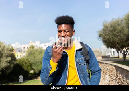 Smiling man talking on speaker phone Stock Photo