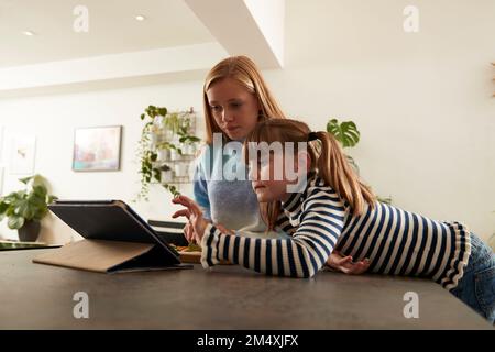 Girl with sister using tablet PC at home Stock Photo