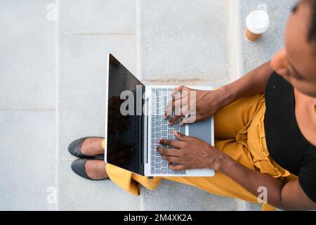 Freelancer working on laptop sitting at staircase Stock Photo