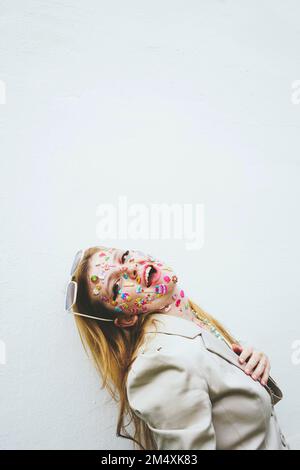 Happy woman with multi colored stickers on face by white background Stock Photo