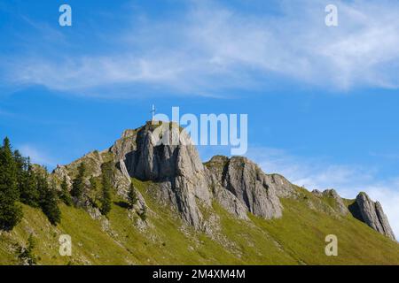 Summit cross on top of Tegelberg mountain under blue sky Stock Photo