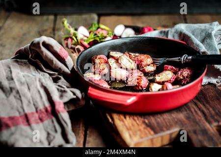 Baked radishes in casserole dish at table Stock Photo
