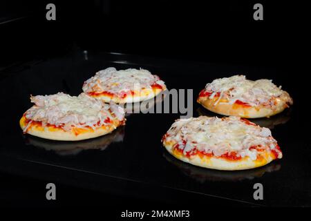 Four baked homemade mini pizzas in electric oven at home Stock Photo