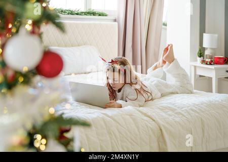 Girl lying on bed and using laptop at home Stock Photo