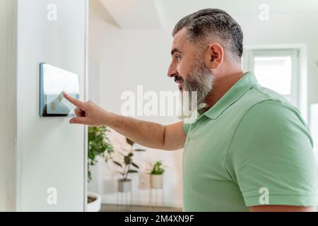 Mature man using tablet PC mounted on wall at home Stock Photo