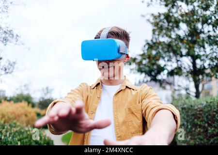 Smiling young man wearing virtual reality headset Stock Photo