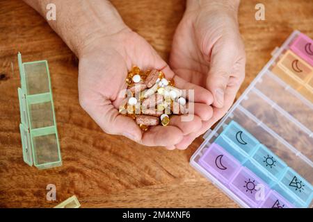 Man holding different pills in hand on table Stock Photo