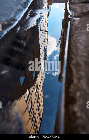 Reflection of building in puddle on road Stock Photo