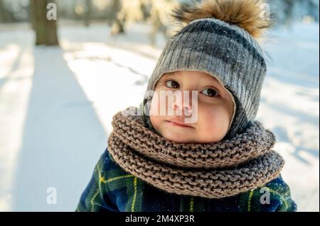 Cute boy wearing scarf and knit hat in winter park Stock Photo