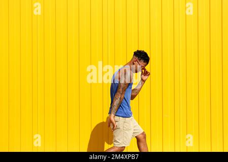 Young man dancing in front of yellow wall Stock Photo