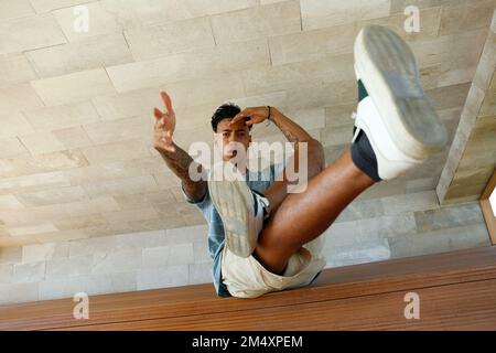 Young man gesturing sitting on bench Stock Photo