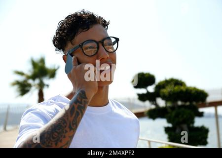 Happy young man talking through mobile phone on sunny day Stock Photo