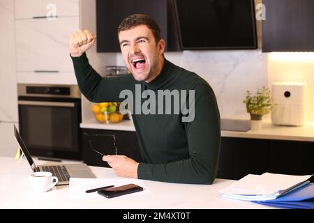 Man celebrating a victory from home office Stock Photo