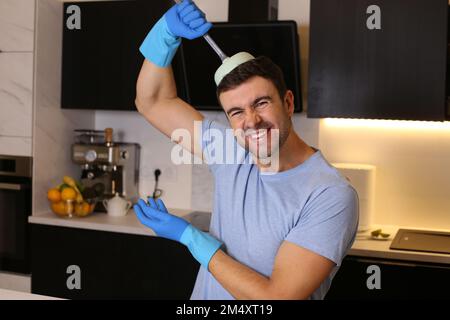 Man holding a plunger in his kitchen Stock Photo