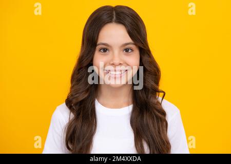 Portrait of cute positive little girl isolated on yellow background. Attractive caucasian child smiling and looking at camera. Stock Photo