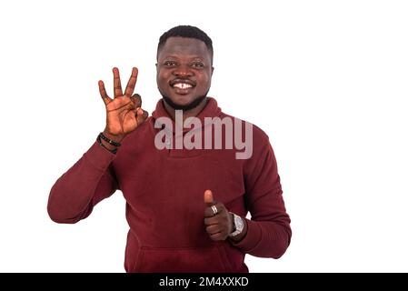 portrait of a handsome happy young man making the okay sign and showing thumbs up while smiling at the camera. Stock Photo