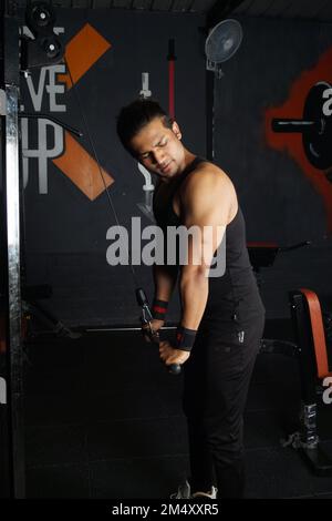 A vertical shot of the South Asian man doing biceps in the gym Stock Photo