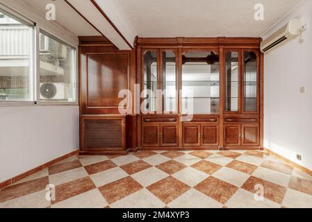 A wooden bookcase with a mirror interior inside the cabinets with glass shelves and stoneware floors in two colors Stock Photo