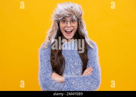 School girl in winter clothes and warm hat. Winter holiday vacation. Child fashion model. Excited face, cheerful emotions of teenager girl. Stock Photo