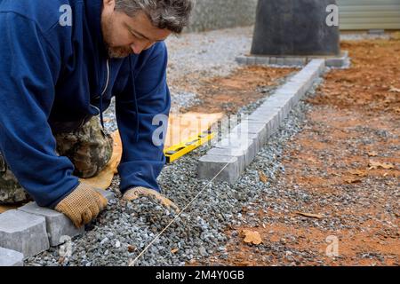 An expert paver worker lays stones on ground for paving of pathway by master. Stock Photo