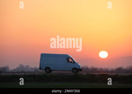 Small cargo van driving on highway hauling goods. Delivery transportation and logistics concept Stock Photo