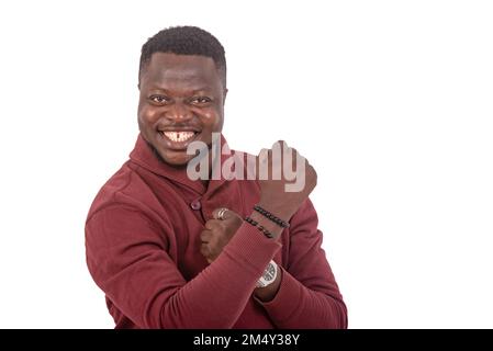 portrait of a handsome young man laughs with clenched fists while smiling at the camera. Stock Photo