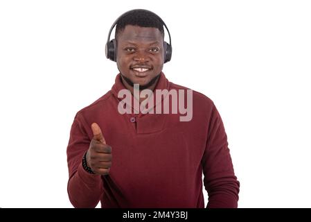 portrait of a handsome young man wearing wireless headphones and showing his thumb while smiling at the camera. Stock Photo