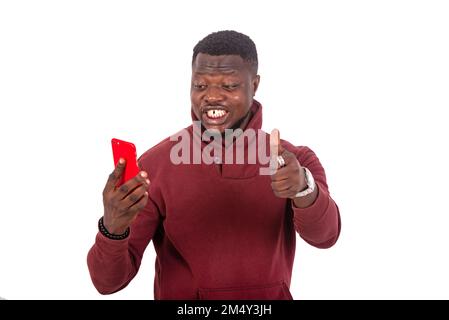 handsome happy young man looking at his mobile phone and showing his thumb. Stock Photo