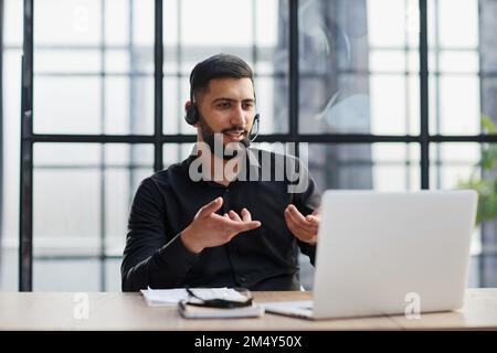 Young handsome male customer support phone operator with headset working in his office. Stock Photo