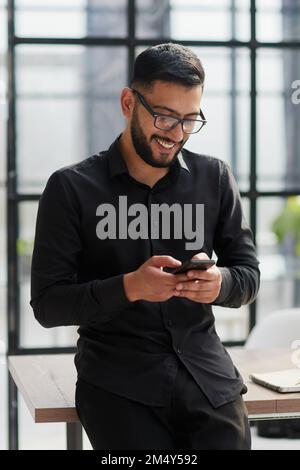 Young casual Businessman holding and using smartphone for sms messages Stock Photo