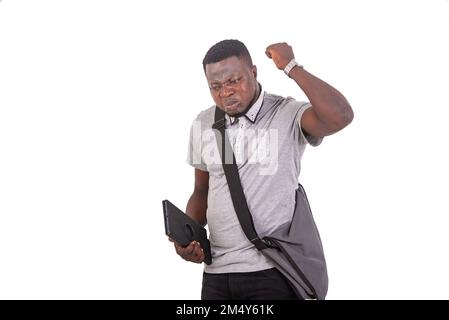 handsome displeased young man carrying a bag over his shoulder and holding a digital tablet. Stock Photo