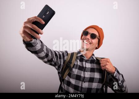 Young traveler boy takes a selfie smiling, studio photo with white background, mock up Stock Photo
