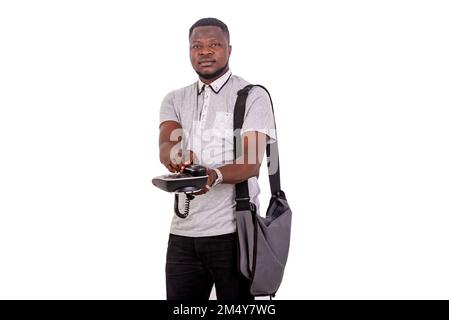 portrait of a young man carrying a bag over his shoulder giving a mobile phone while looking at the camera. Stock Photo