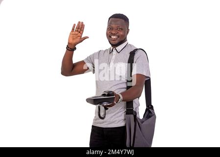 portrait of a young man raising his hand while giving a mobile phone while smiling at the camera. Stock Photo