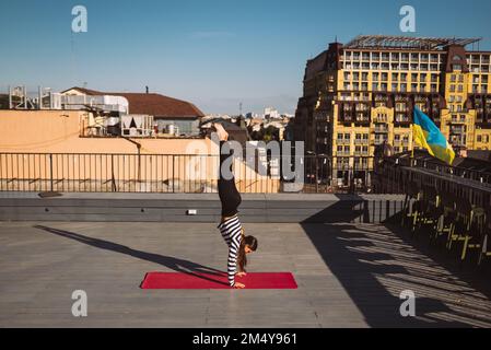 Young woman working out outdoors and doing yoga handstand exercise Stock Photo