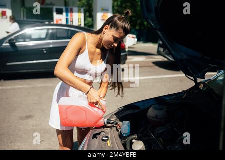 Young woman pouring antifreeze car screen wash liquid into car Stock Photo