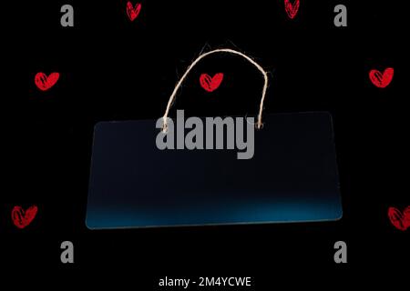 Rectangular shaped black notice board and red hearts on black background Stock Photo