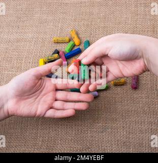 Used color crayons and a hand giving out some Stock Photo
