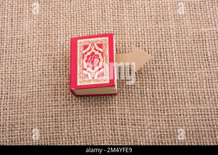 Paper arrow and Islamic Holy Book Quran in mini size Stock Photo