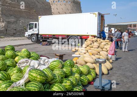 BUKHARA, UZBEKISTAN - SEPTEMBER 09, 2022: Trade of melons and watermelons at the ancient fortress wall. Street market in Bukhara Stock Photo