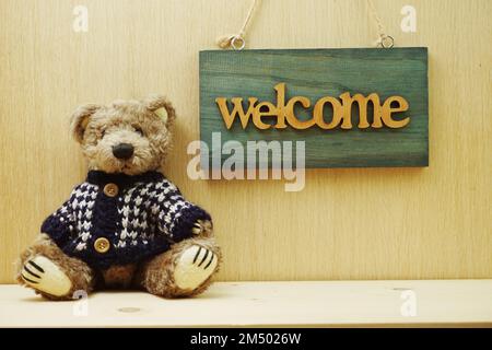 Welcome Sign and Teddy bear on wooden background Stock Photo