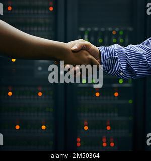 Making deals in the data center. two men shaking hands in a data center. Stock Photo