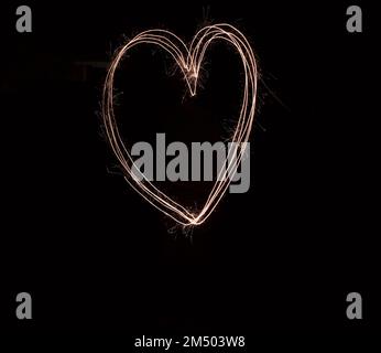 Love and light in the darkness. a hart being drawn with a sparkler through use of light painting outside at night. Stock Photo