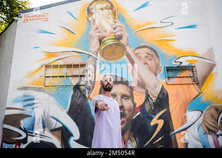 Buenos Aires, Argentina. 23rd Dec, 2022. The artist, Maximiliano Bagnasco, poses in front of his work in Buenos Aires. The Argentine artist, Maximiliano Bagnasco is the first to capture Argentina's triumph in Qatar 2022 in a mural where Lionel Messi is seen lifting the FIFA World Cup in the Palermo neighborhood, Buenos Aires. Credit: SOPA Images Limited/Alamy Live News Stock Photo