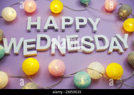 Happy Wednesday alphabet letters with LED cotton balls on purple background Stock Photo